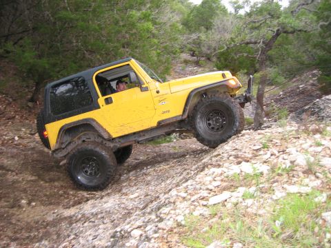 2001 Jeep Wrangler - A yellow 2001 Jeep Wrangler navigates a steep, rocky incline during an off-road excursion.