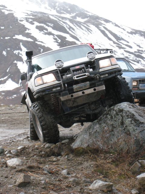 2000 Ford E350 - Off-road truck navigates a rocky obstacle with a second vehicle in the background.