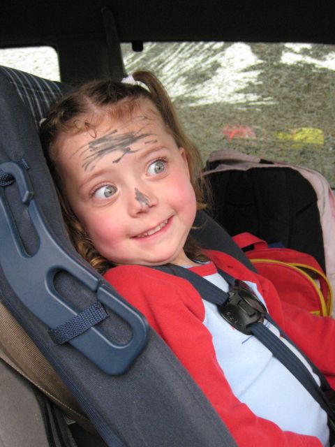 2000 Ford E350 - A child with a playful expression has dirt smeared across their face while sitting in a car seat.