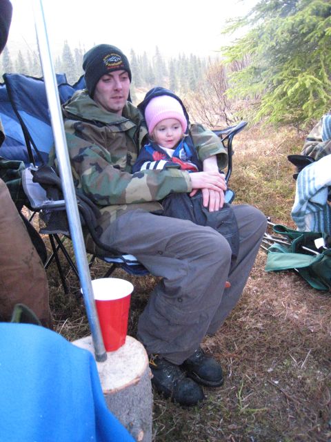 2000 Ford E350 - A man and child sit in camping chairs outdoors, with a red cup and log nearby.