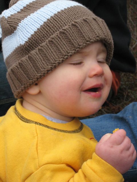2000 Ford E350 - A baby in a brown and white striped beanie and yellow shirt is shown with eyes closed and mouth open, holding a snack.
