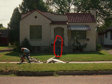 1986 Ford Bronco - A person stands on the lawn in front of a small house, with a bicycle nearby.
