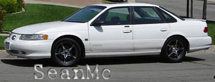 1993 Ford Taurus - This white sedan has a distinctive body style and aftermarket wheels.