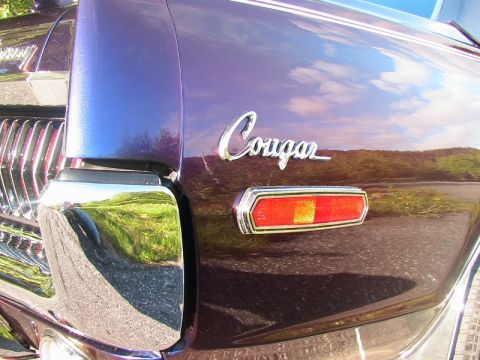 1968 Mercury Cougar - A close-up view of the rear of a purple 1968 Mercury Cougar, showing the Cougar emblem and a taillight.