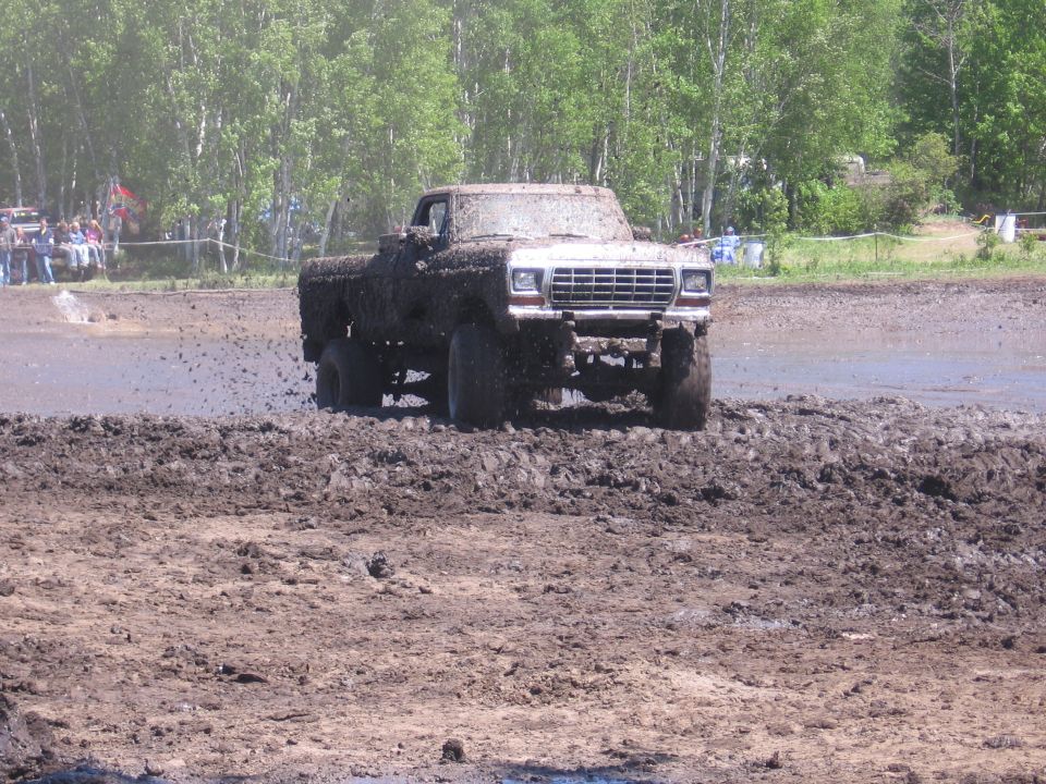 Pickup truck covered in mud driving through a mud pit