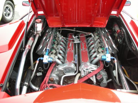 1998 Ford Crown Victoria - The engine bay of a red sports car is open, revealing a complex V12 engine with custom modifications.