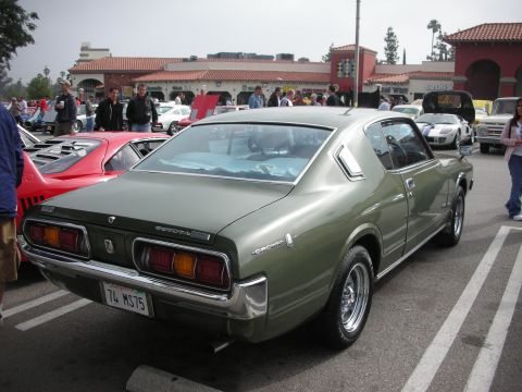 1998 Ford Crown Victoria - A vintage Toyota Crown coupe is parked at a car meet, with other vehicles and spectators in the background.
