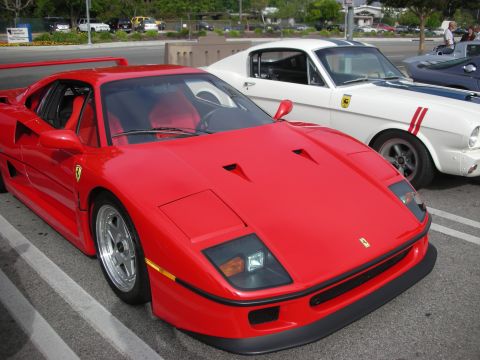 1998 Ford Crown Victoria - A red Ferrari sports car is parked in a lot next to a white classic car with racing stripes.