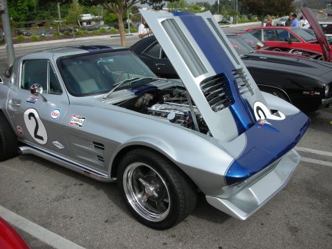 1998 Ford Crown Victoria - A classic Corvette Stingray is displayed with its hood open, revealing the engine, parked among other vehicles.