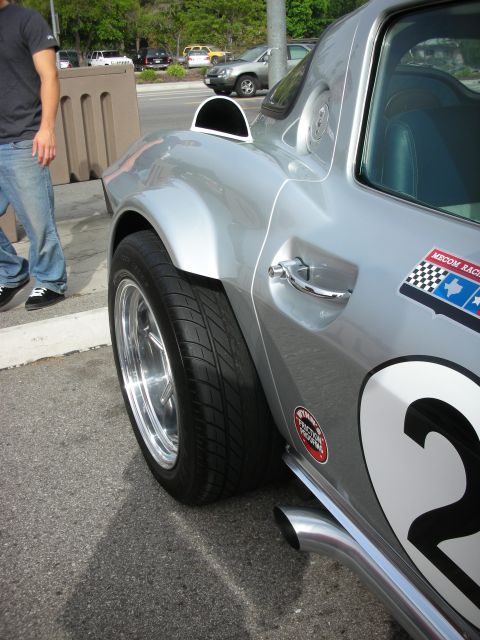 1998 Ford Crown Victoria - A silver sports car with racing decals, including a checkered flag and a Texas star, is seen from the side.
