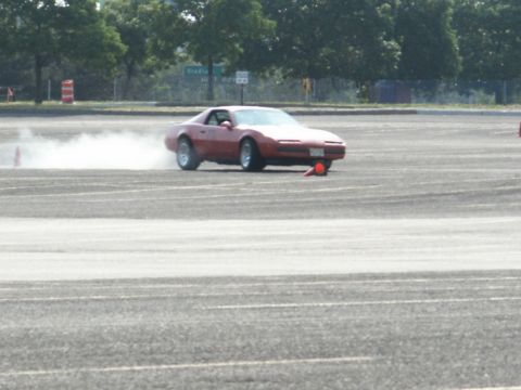 2001 Mercury Grand Marquis - A red sports car is seen drifting on a paved surface, creating a cloud of smoke.