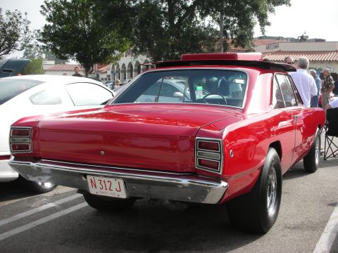 1998 Ford Crown Victoria - A red 1967 Dodge Dart sedan is parked at a car meet, showing its rear end and drag racing tires.