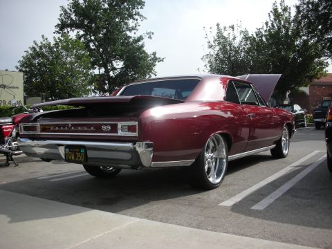 1998 Ford Crown Victoria - Burgundy 1966 Chevrolet Chevelle SS with custom wheels and spoiler parked in a lot.