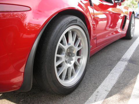 1998 Ford Crown Victoria - A red sports car is parked in a lot, showing a close-up view of its wheel and side panel.