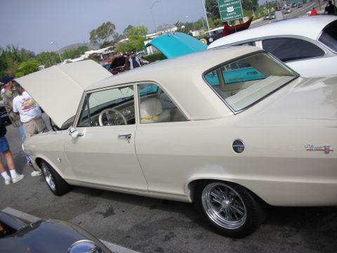 1998 Ford Crown Victoria - Cream 1967 Chevrolet Nova II coupe with white interior and aftermarket wheels at a car meet.