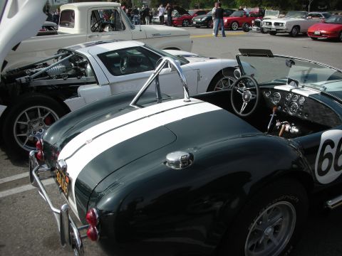 1998 Ford Crown Victoria - A dark green convertible with white racing stripes and the number 66 is parked next to other vehicles at a car meet.