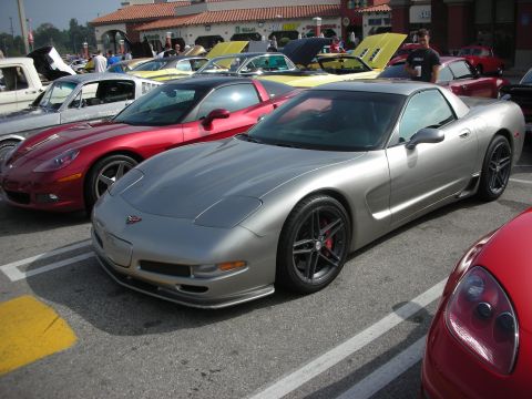 1998 Ford Crown Victoria - A silver Chevrolet Corvette C5 is parked next to other vehicles at an outdoor gathering.