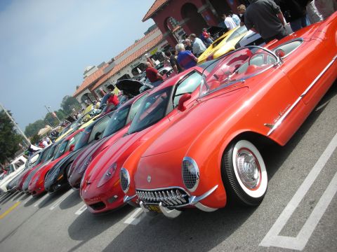1998 Ford Crown Victoria - A row of classic cars, including a prominent red one with a distinctive grille, are parked at an outdoor event.