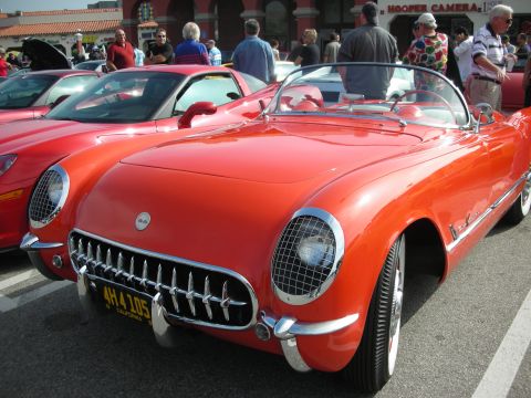 1998 Ford Crown Victoria - A classic red convertible sports car is parked at a car meet, with a modern car beside it.
