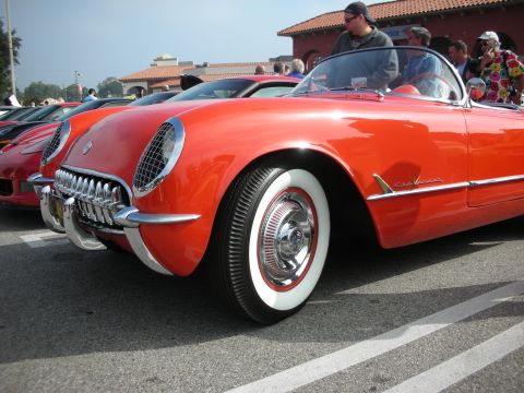 1998 Ford Crown Victoria - A classic red convertible with distinctive chrome accents and whitewall tires is displayed at an outdoor event.