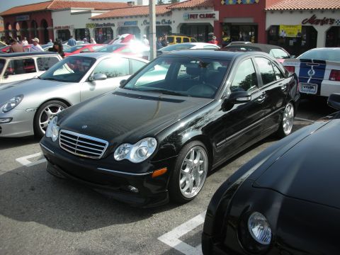 1998 Ford Crown Victoria - A black Mercedes-Benz sedan is parked in a lot alongside other vehicles.