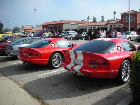 1998 Ford Crown Victoria - Two red Dodge Viper GTS cars with white racing stripes parked side-by-side at a car meet.