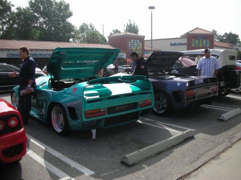 1998 Ford Crown Victoria - Two custom sports cars are displayed with their engines accessible at an outdoor gathering.