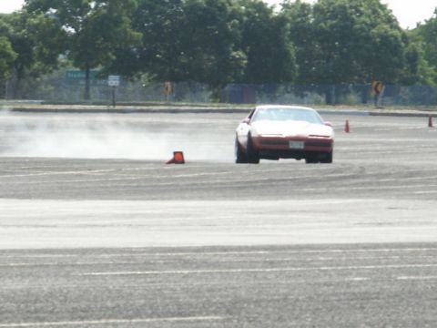 2001 Mercury Grand Marquis - A red sports car is seen drifting on a track, kicking up smoke as it navigates around orange cones.