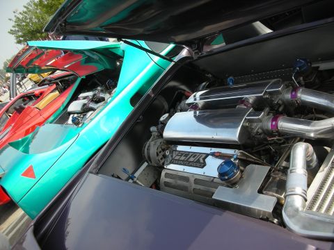 1998 Ford Crown Victoria - Close-up of a custom engine bay with twin turbos and polished components, alongside other exotic cars.