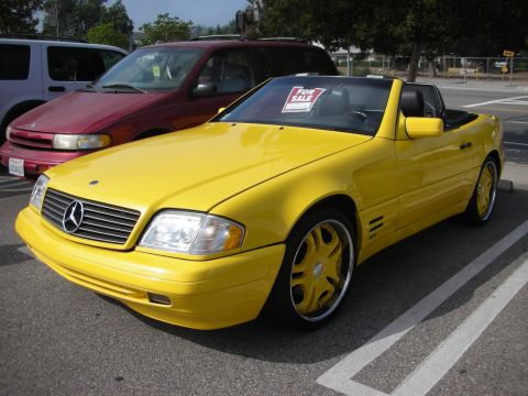 1998 Ford Crown Victoria - Yellow Mercedes-Benz convertible parked in a lot with other vehicles. "FOR SALE" sign visible.