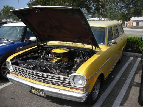 1998 Ford Crown Victoria - A yellow station wagon is parked with its hood open, revealing the engine compartment. Another vehicle is parked beside it.