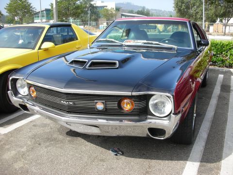 1998 Ford Crown Victoria - A classic 1970 AMC AMX with a distinctive hood scoop and grille is parked in a lot.
