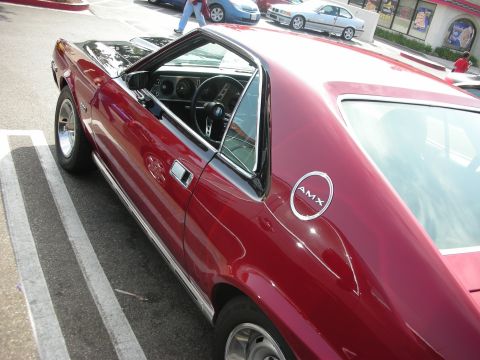 1998 Ford Crown Victoria - AMC AMX parked in a lot, side view shows the distinctive body lines and fender emblem.