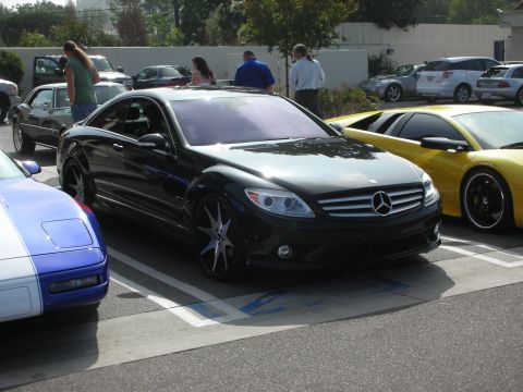 1998 Ford Crown Victoria - Several cars are parked in a lot, including a black Mercedes-Benz coupe, a blue and white Corvette, and a yellow sports car.