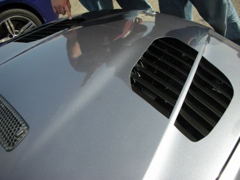 1998 Ford Crown Victoria - Close-up of a car's hood showing vents and a reflection of people.