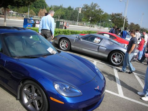 1998 Ford Crown Victoria - A blue Chevrolet Corvette is parked next to a silver Ford GT at a car meet.
