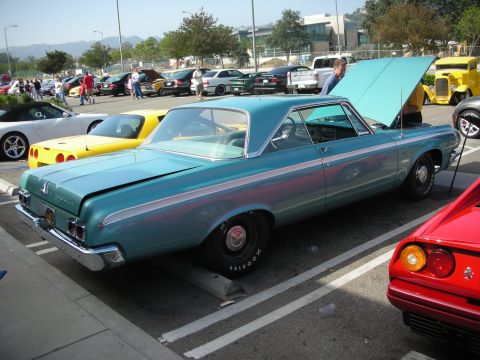 1998 Ford Crown Victoria - A teal 1964 Dodge Polara coupe is parked at a car meet with its hood open, alongside other vehicles.