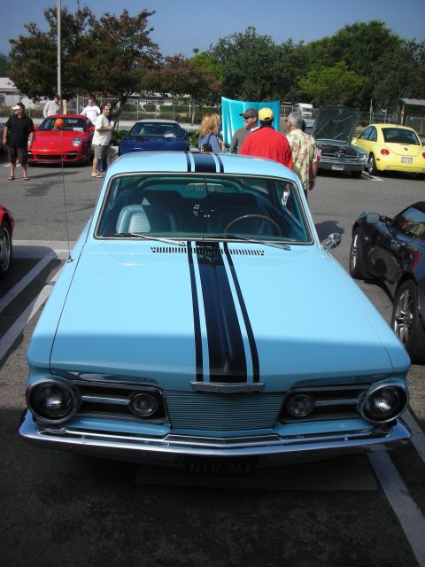 1998 Ford Crown Victoria - A light blue classic car with black racing stripes is parked at an outdoor car meet, with other vehicles visible in the background.