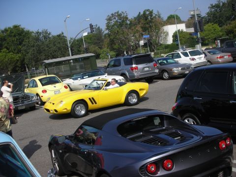 1998 Ford Crown Victoria - A yellow convertible sports car is parked among other vehicles on a sunny day.