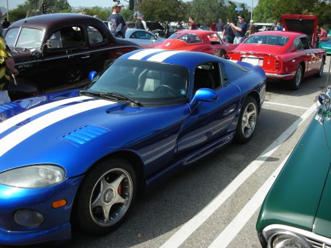 1998 Ford Crown Victoria - A blue Dodge Viper with white stripes is parked at a car meet with other vehicles.