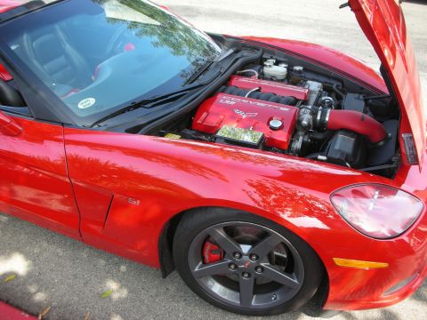 1998 Ford Crown Victoria - A red Chevrolet Corvette Z06 is shown with its hood open, revealing the engine bay and Z06 badging.