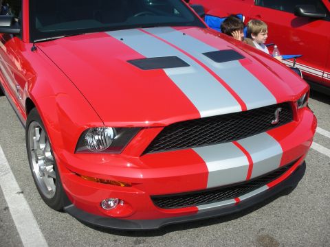 1998 Ford Crown Victoria - Front view of a red Ford Mustang Shelby GT500 with silver stripes and a Cobra emblem.