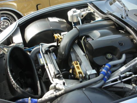 1998 Ford Crown Victoria - A close-up view of a car's engine bay, carbon fiber covers and bright gold suspension parts. Another vehicle is visible in the background.