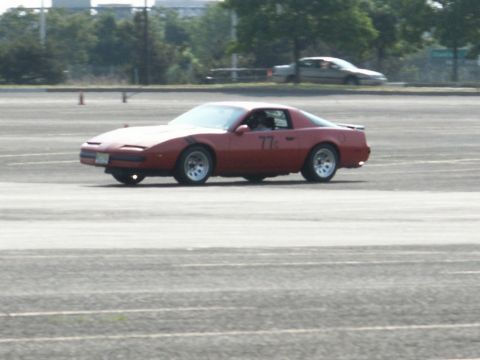2001 Mercury Grand Marquis - A red sports car with the number 77 displayed on its door navigates a track.
