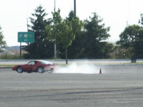 2001 Mercury Grand Marquis - A red sports car is seen drifting on a paved surface, creating a cloud of smoke.