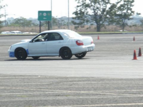 2001 Mercury Grand Marquis - A white Subaru Impreza WRX sedan is seen on a track, likely participating in a timed event or driving school, with orange cones marking the…
