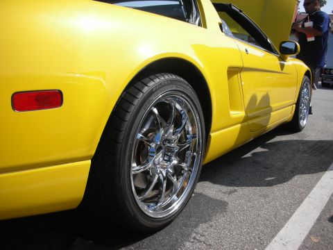 1998 Ford Crown Victoria - A bright yellow sports car is captured from the side, its chrome wheels and a red taillight detail.