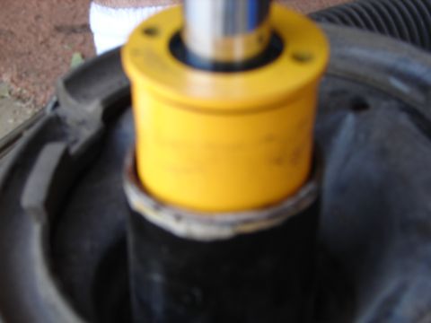 1992 Ford Taurus - A yellow suspension component is mounted on a black shock absorber, part of a vehicle's suspension system.