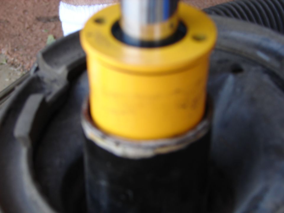 Close-up of a yellow suspension strut mount on a black shock absorber