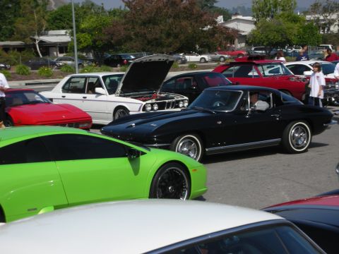 1998 Ford Crown Victoria - A collection of cars, including a black 1963 Chevrolet Corvette coupe, are gathered at an outdoor event.